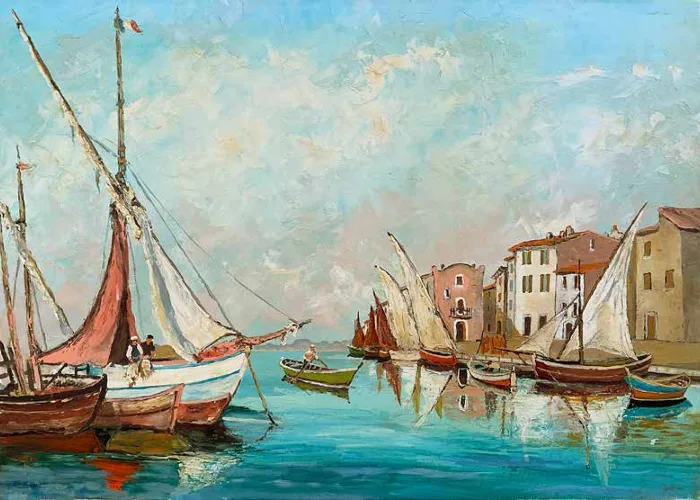 Voiliers de pêche amarrés dans un port provençal par temps calme, village aux toits de tuiles en arrière-plan.