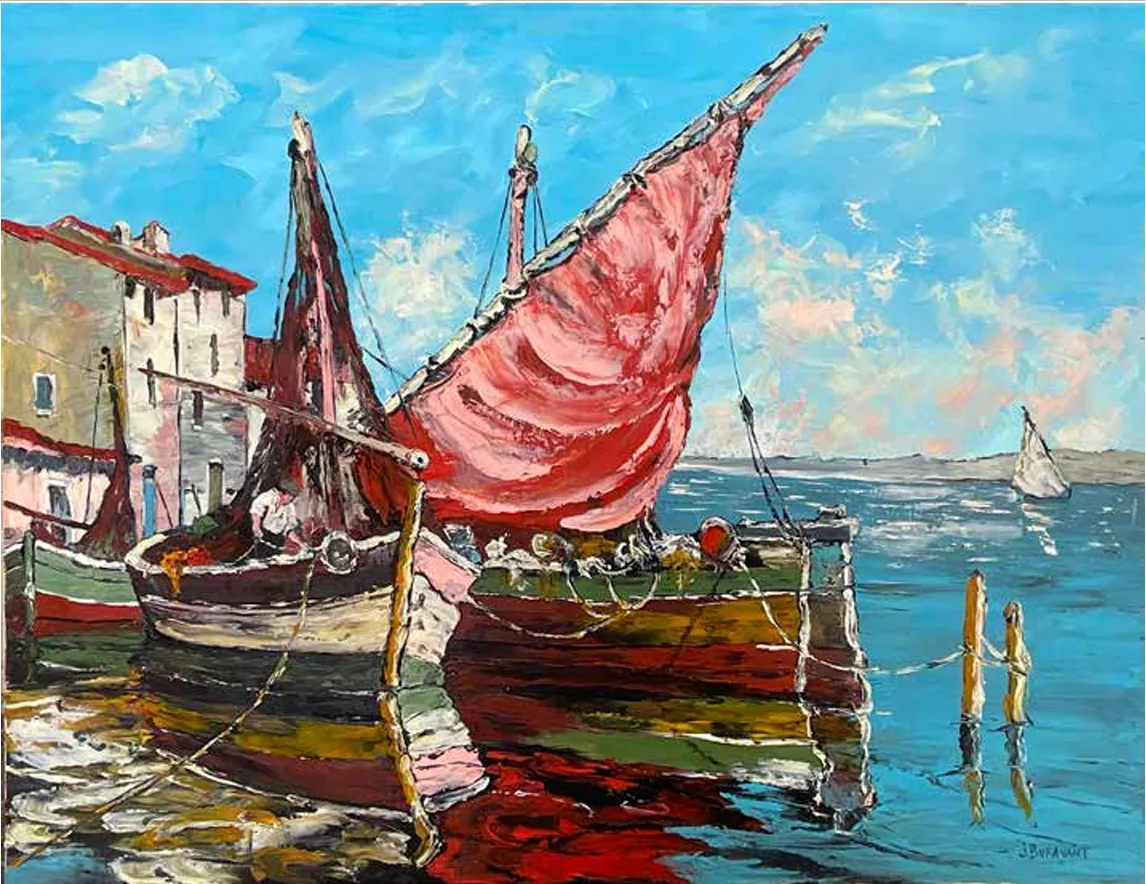 Voilier à la grand-voile rouge amarré près d'un quai, reflets sur l'eau bleue, voilier blanc au loin.